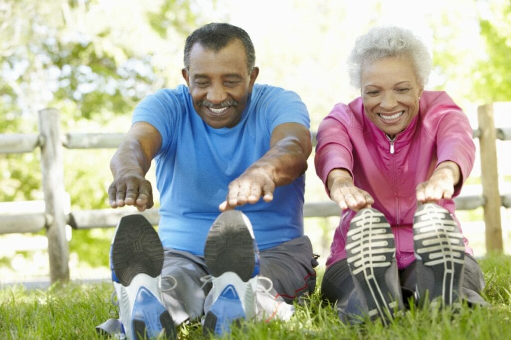 A man and woman sitting on the grass with their feet in the air.
